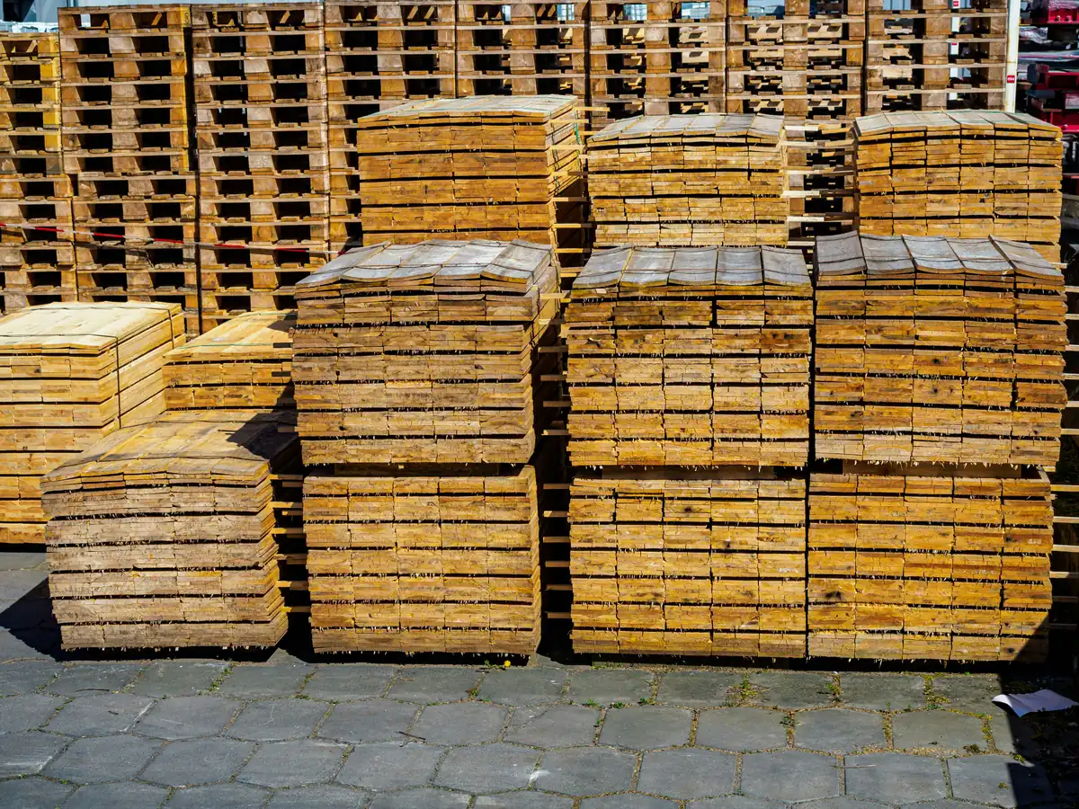 Stacks of inspected, sorted, and graded used wooden pallets in an outdoor storage yard.